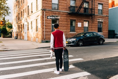 The man in red and white long sleeve shirt and black trousers walk on the sidewalk in the parade
